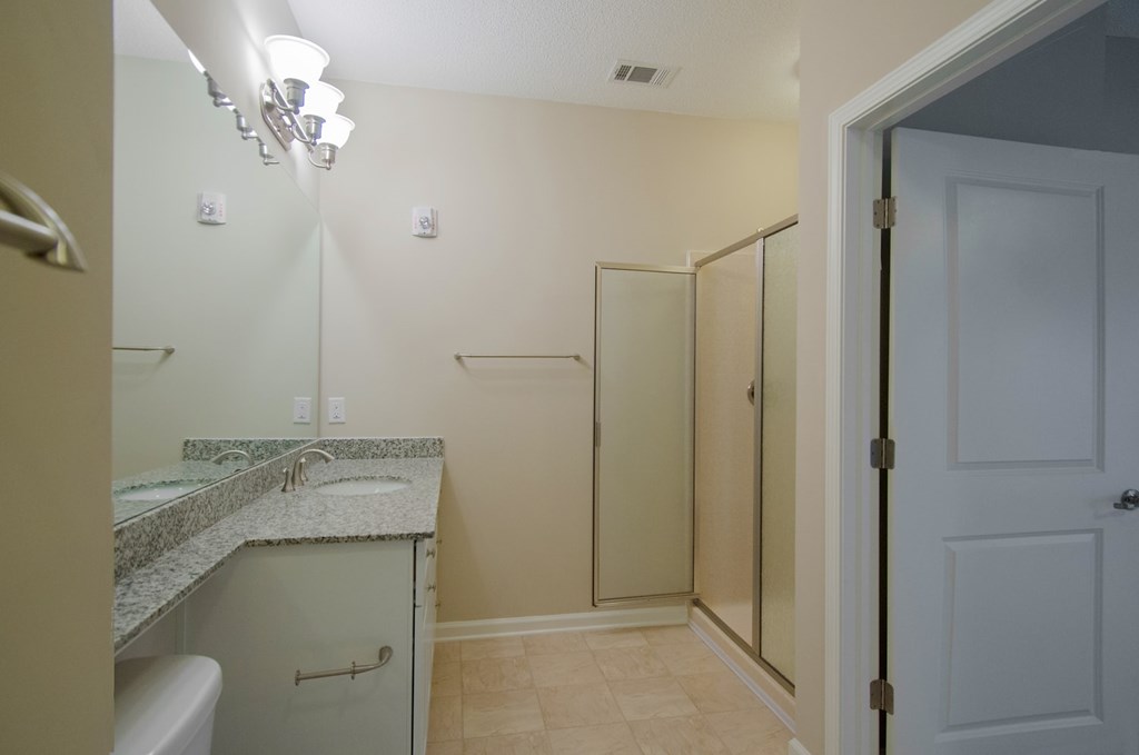 A bathroom with a marble countertop and a walk-in shower.