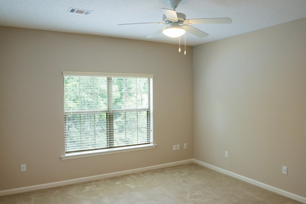 A room with a ceiling fan and a window with blinds.