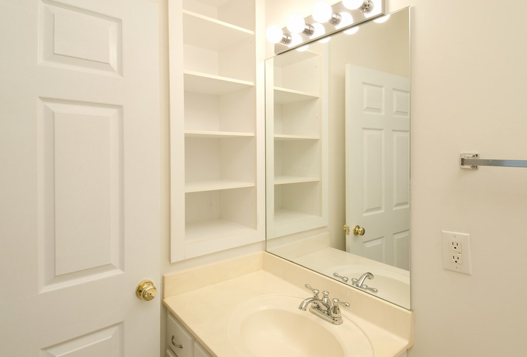 A white bathroom with a sink and mirror.