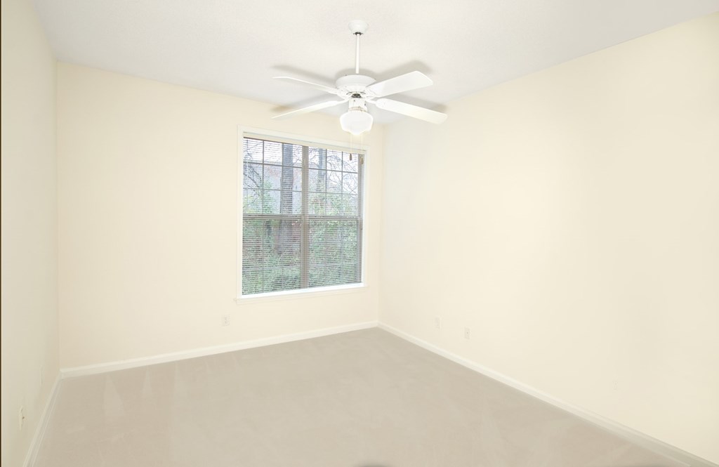 Empty room with a window and a ceiling fan.