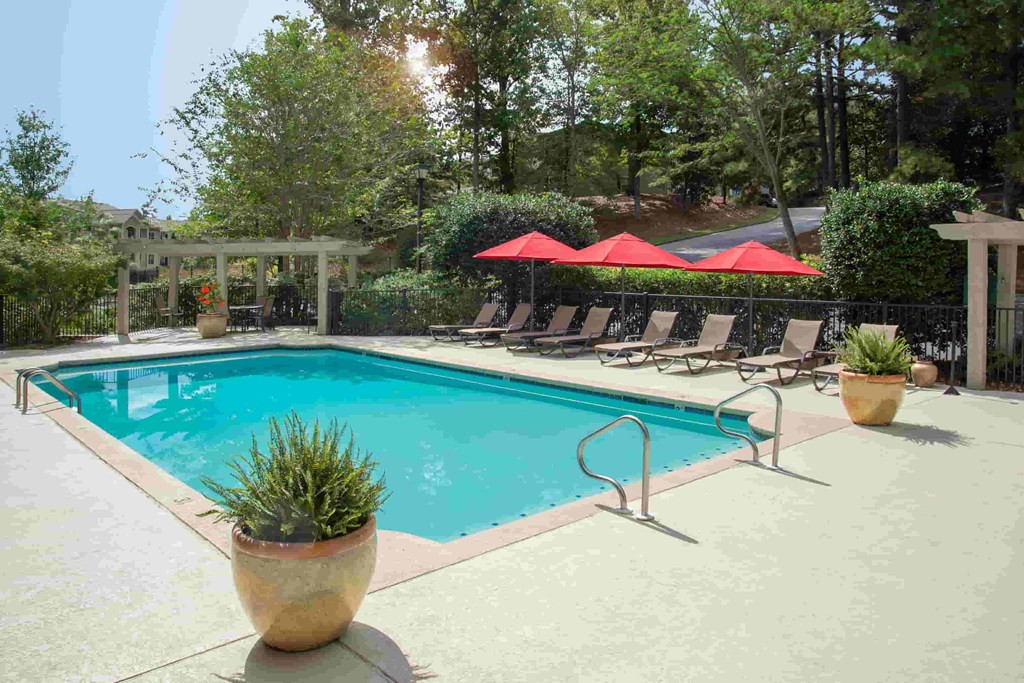 A pool with a red umbrella and a potted plant.