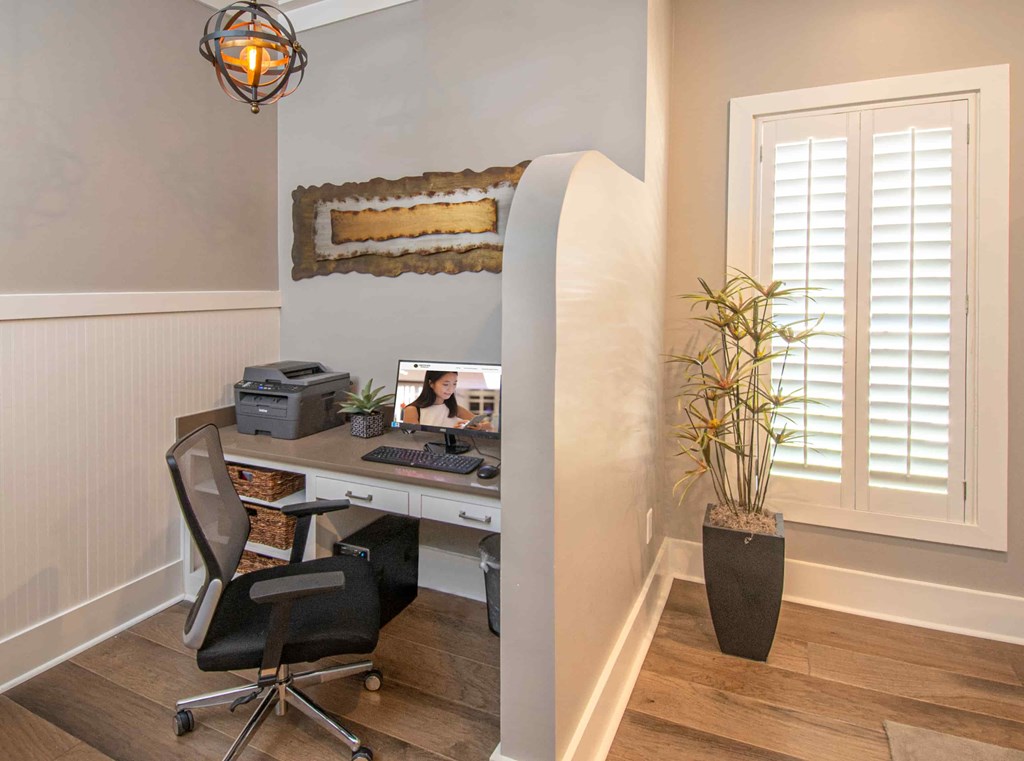 A home office with a desk, chair, and a potted plant.