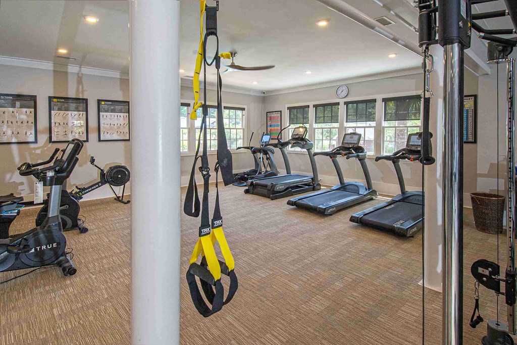 A gym with treadmills, exercise bikes, and TRUMP fitness equipment.