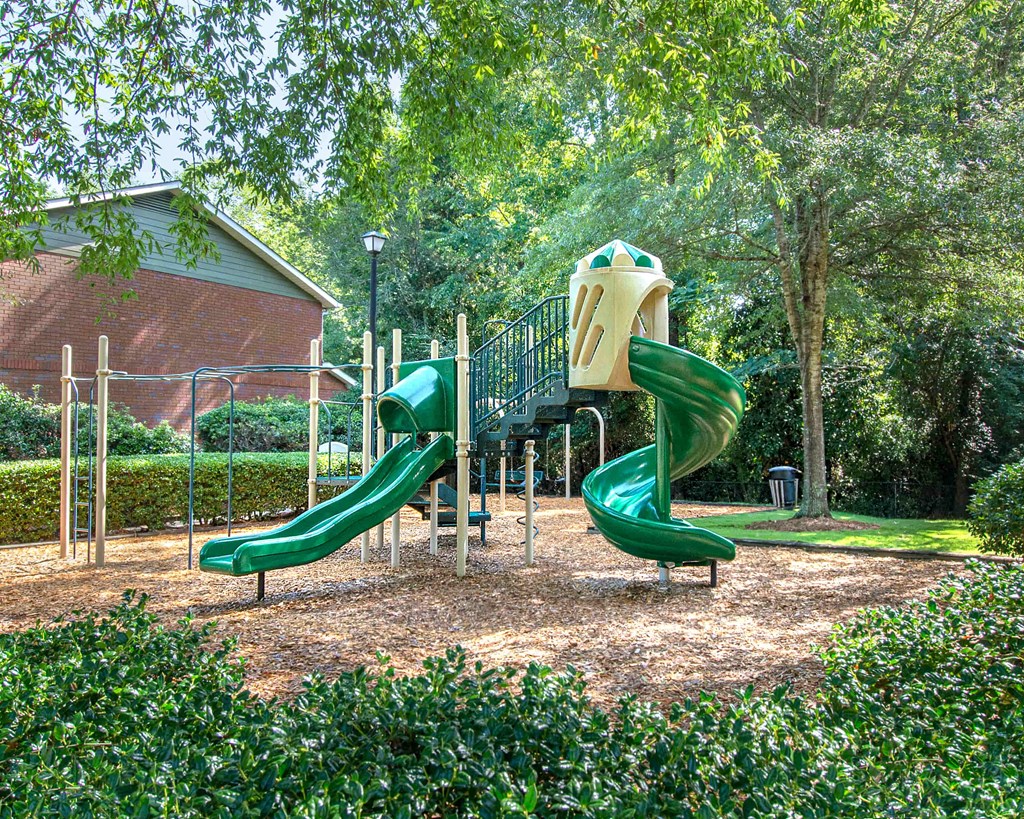 A playground with a green slide and a yellow and green structure.