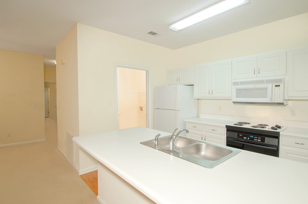 A kitchen with white cabinets and appliances.