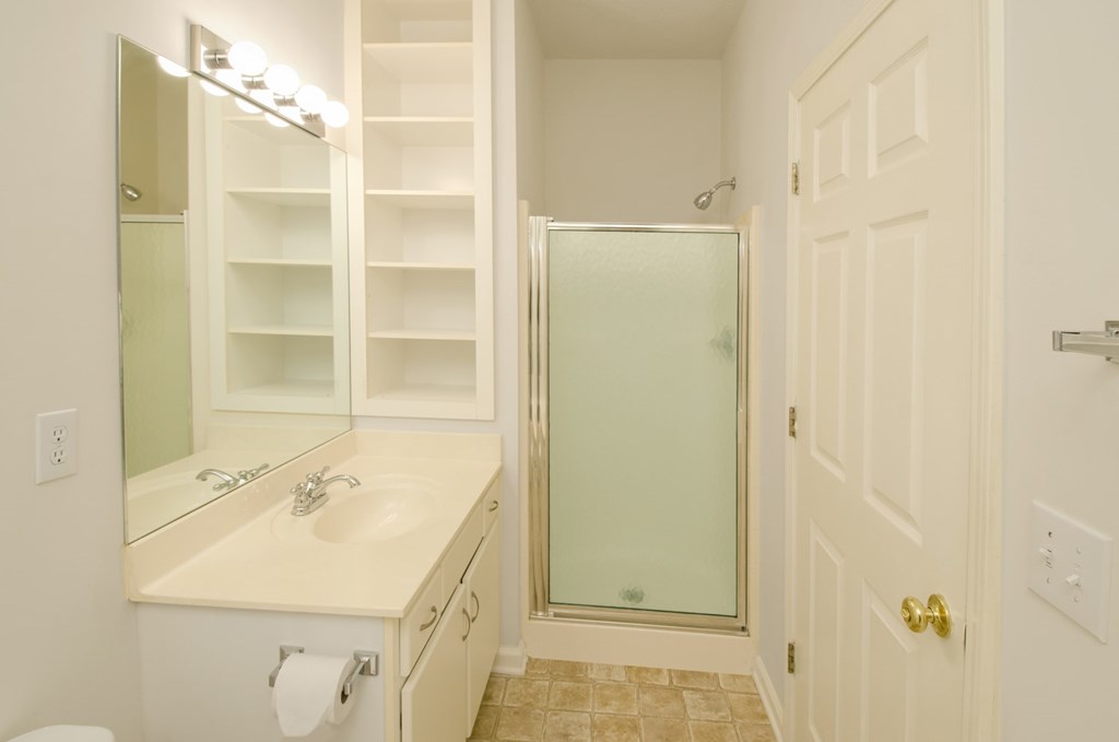 A bathroom with a sink, mirror, and shower.