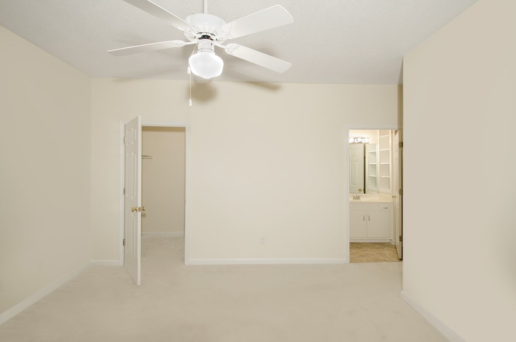 A white room with a ceiling fan and a door.