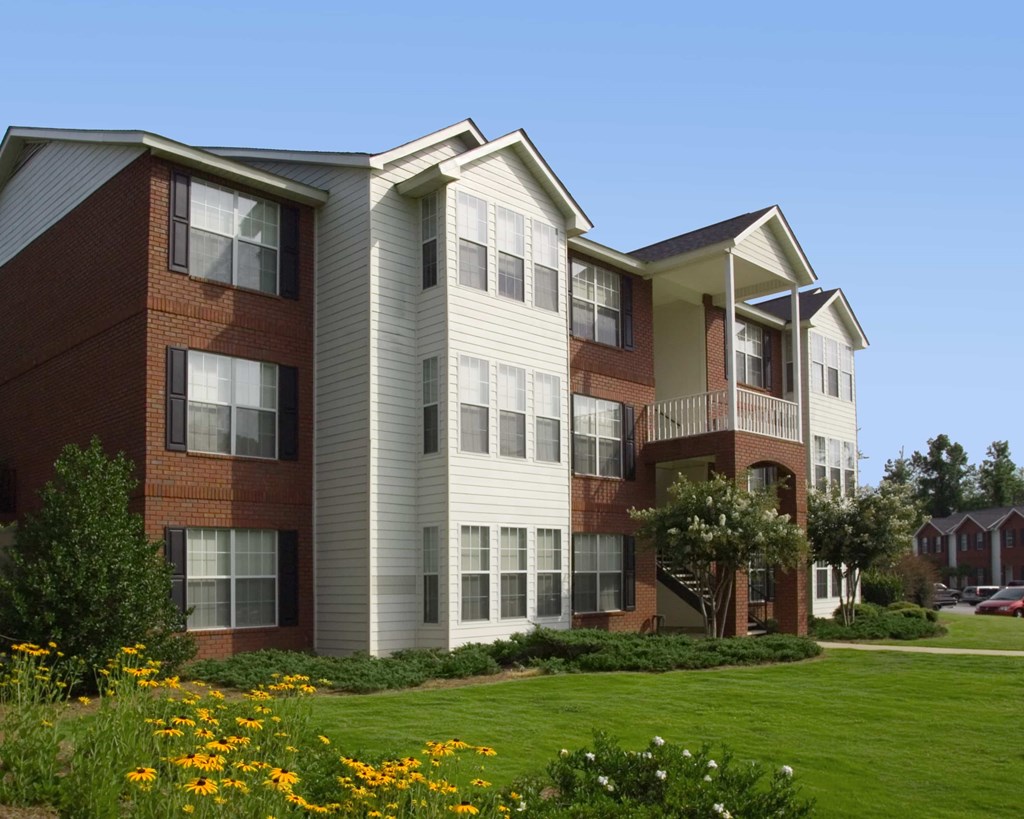 A row of townhouses with a green lawn in front.