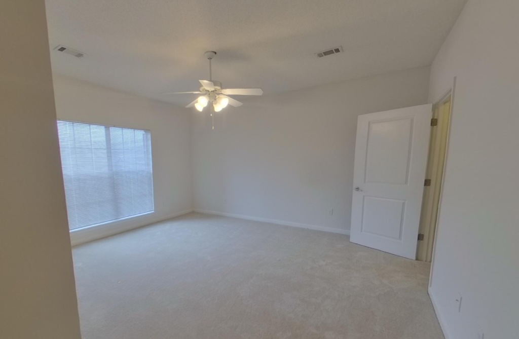 A room with a ceiling fan and a door.