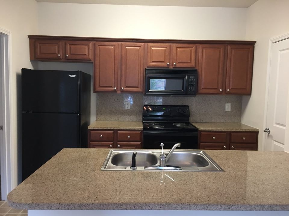A kitchen with black appliances and brown cabinets.