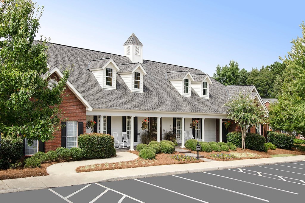 A building with a grey roof and white trim is surrounded by a parking lot.