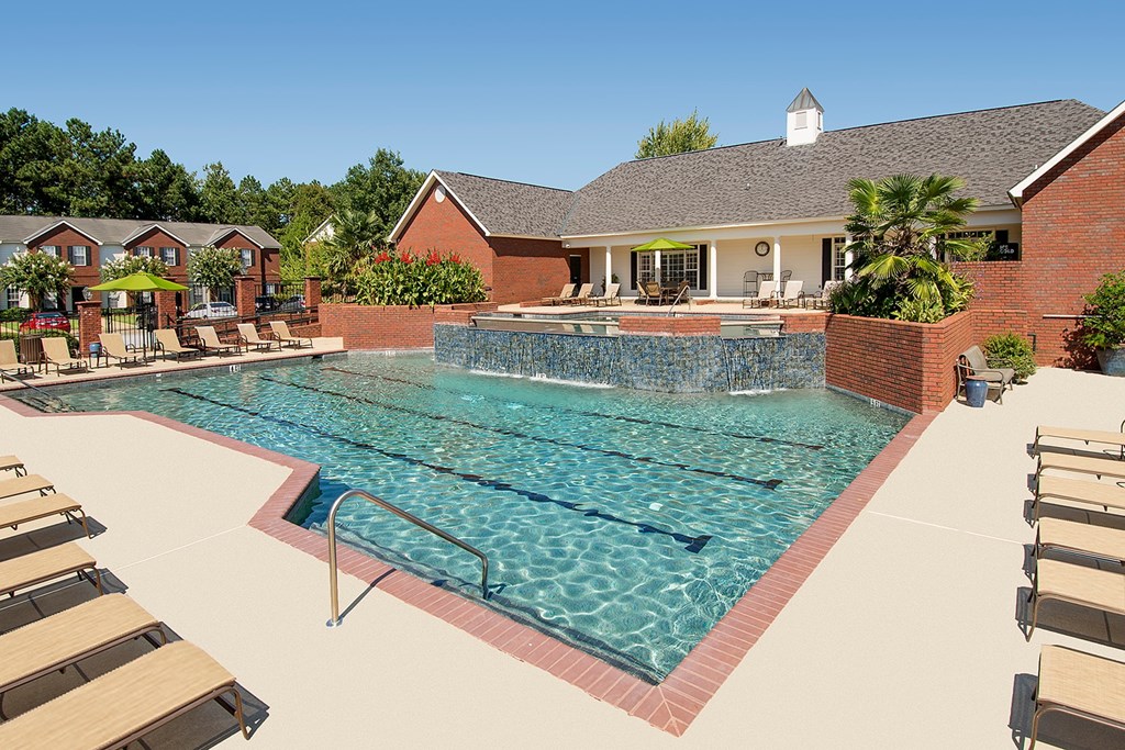 A large swimming pool with a brick wall and sun loungers.