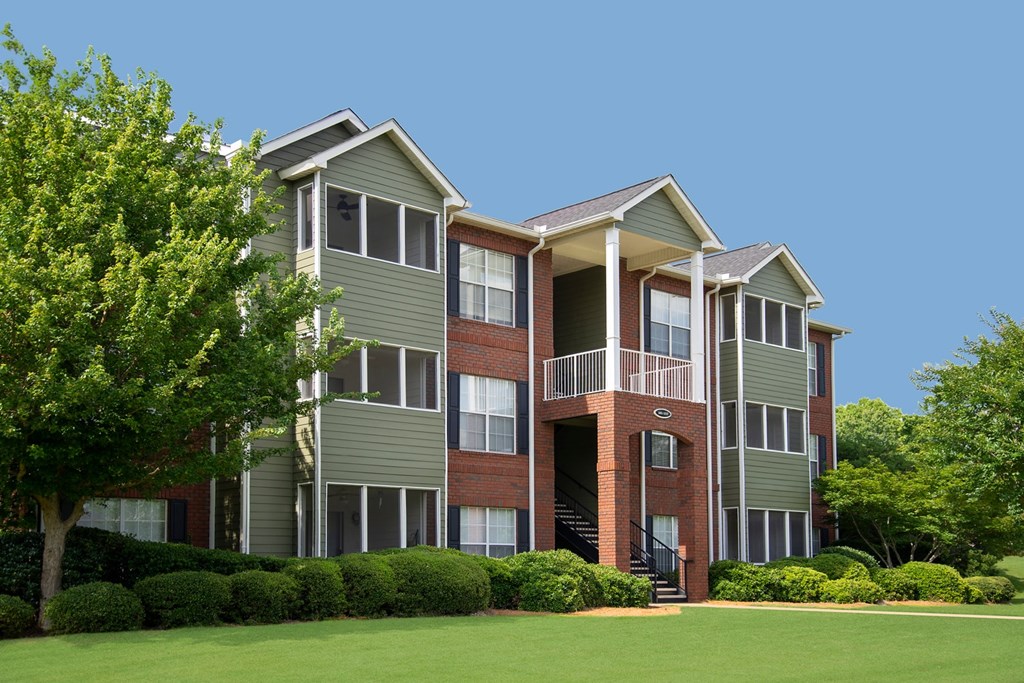 A large apartment building with a green lawn in front.