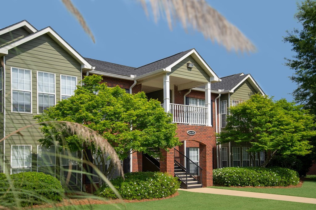 A row of houses with green lawns and trees.