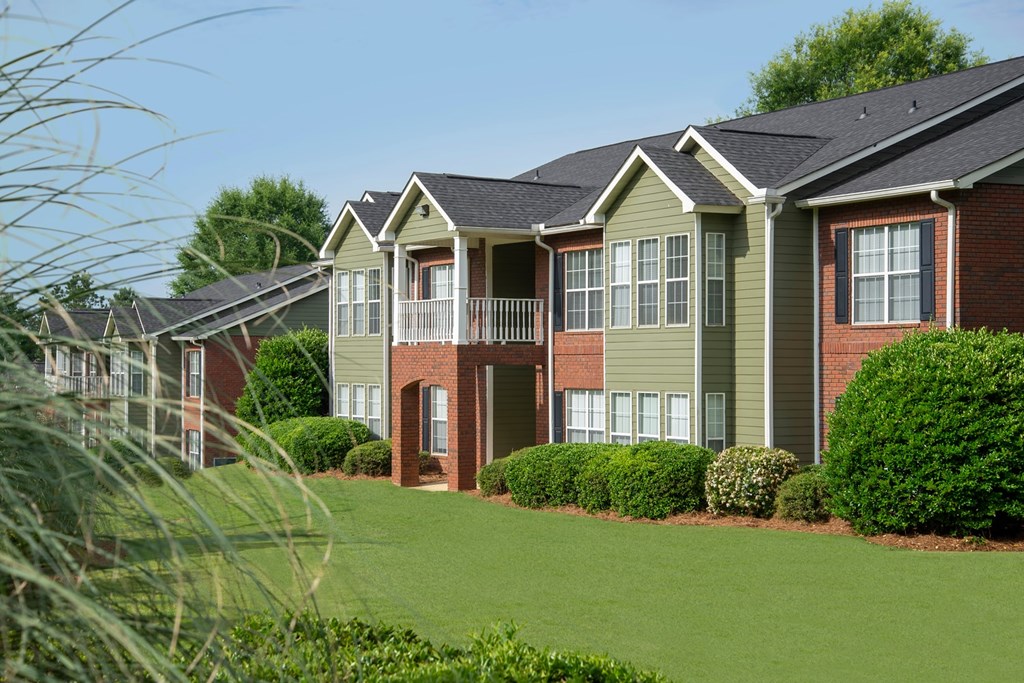 A row of houses with green lawns in front.