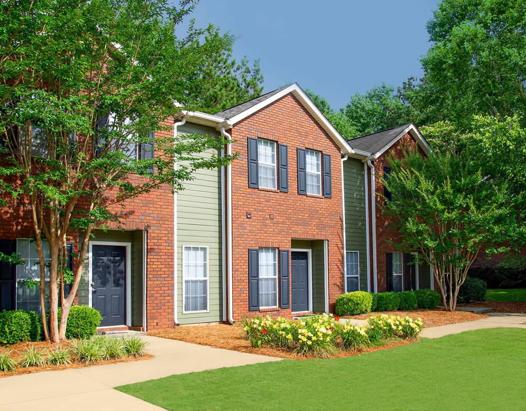 A red brick house with a green lawn in front.