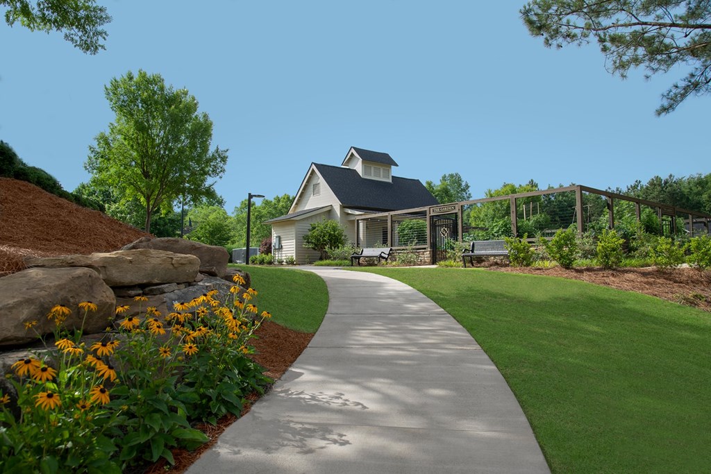 A house with a grey roof and a white fence is surrounded by a garden with orange flowers.