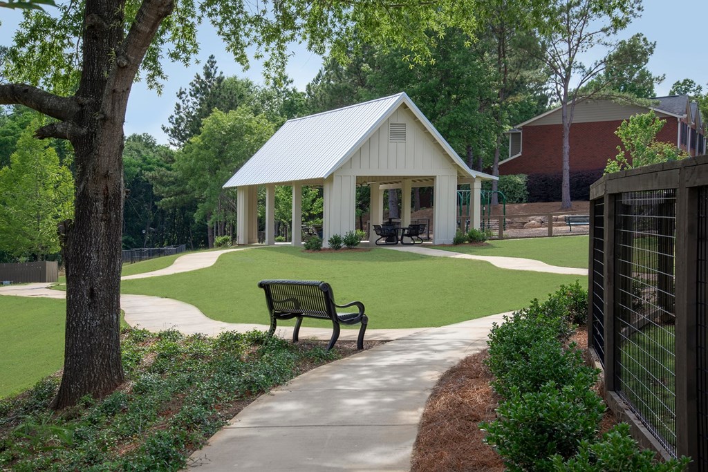 A white pavilion with a black fence and a bench in front of it.