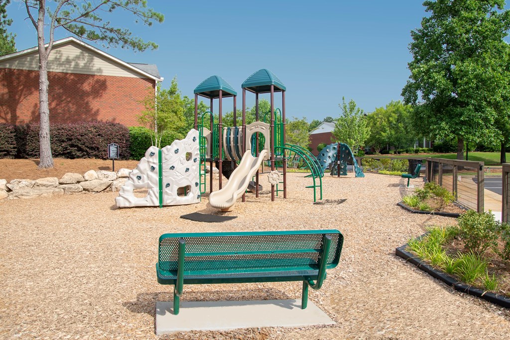 A playground with a green bench and a slide.