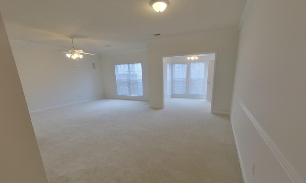 A white room with a ceiling fan and two windows.