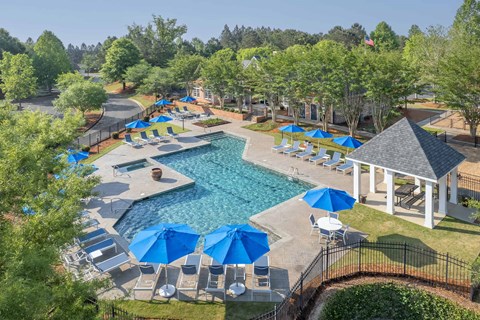A pool surrounded by blue umbrellas and chairs.