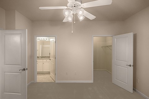 A room with a ceiling fan and two doors.
