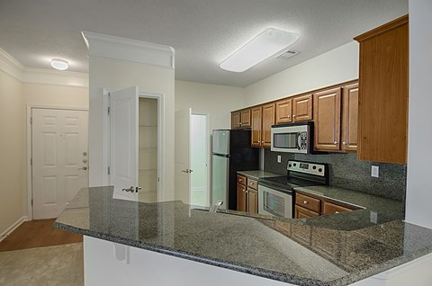A kitchen with granite countertops and wooden cabinets.