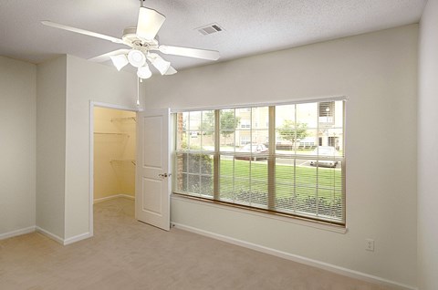 A room with a ceiling fan and a window with blinds.