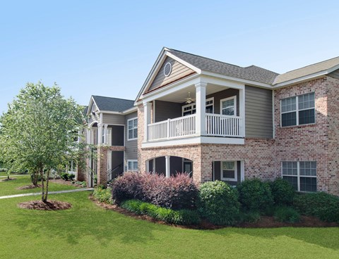 A large two-story brick house with a balcony on the second floor.