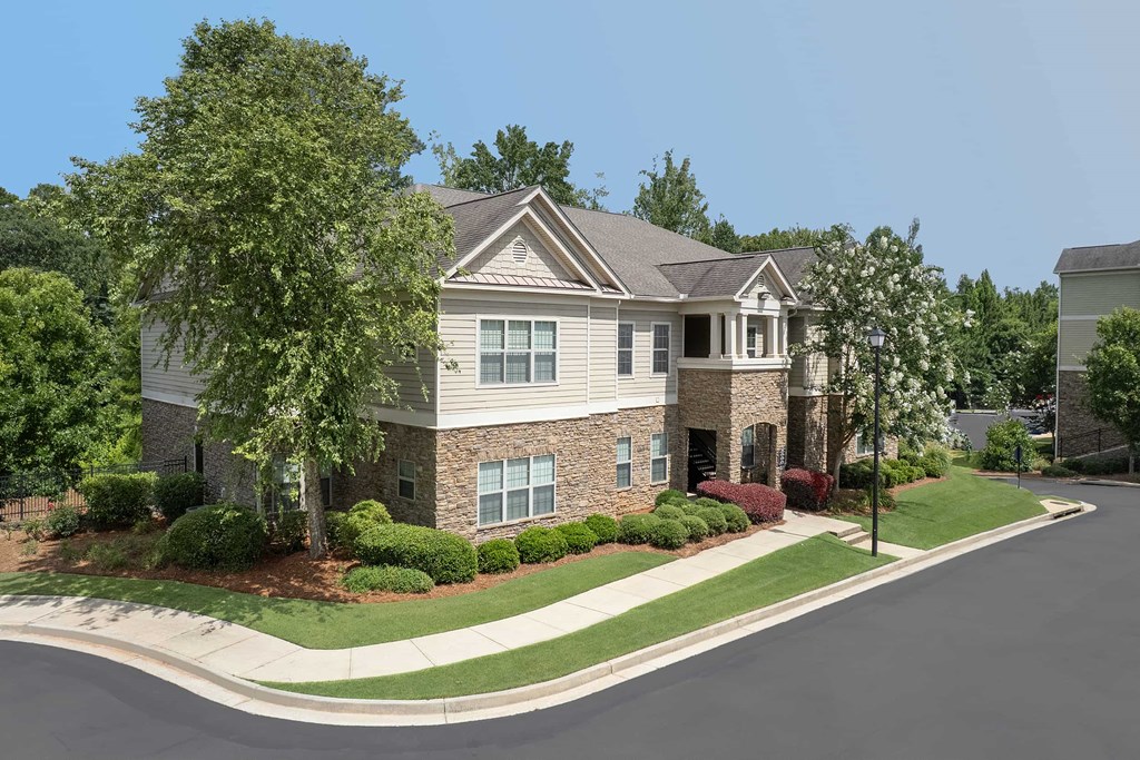 A large house with a grey roof and a driveway in front.