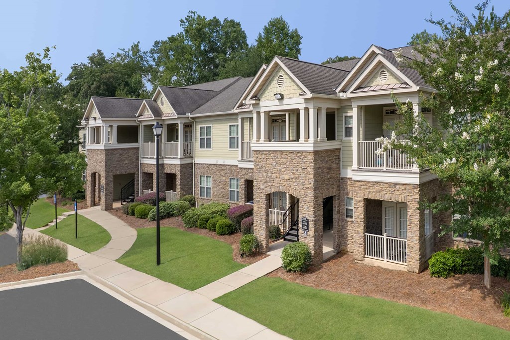 A large, two-story house with a stone facade and a balcony on the second floor.