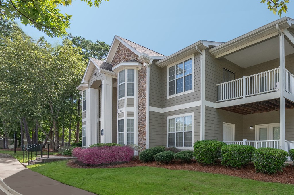 A large house with a balcony and a garden in front.