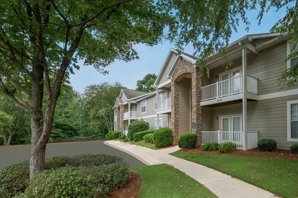 A tree in front of a building with a white fence.