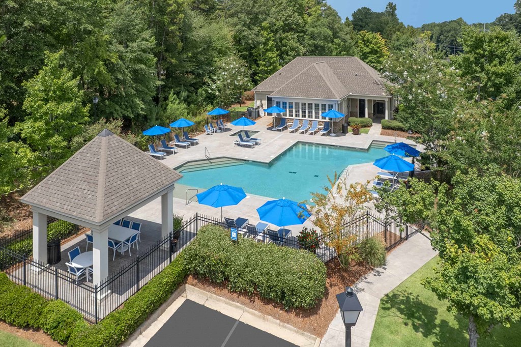 A pool surrounded by trees and a gazebo.