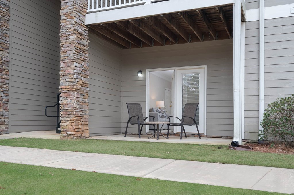 A patio with a table and chairs is on the front porch of a house.