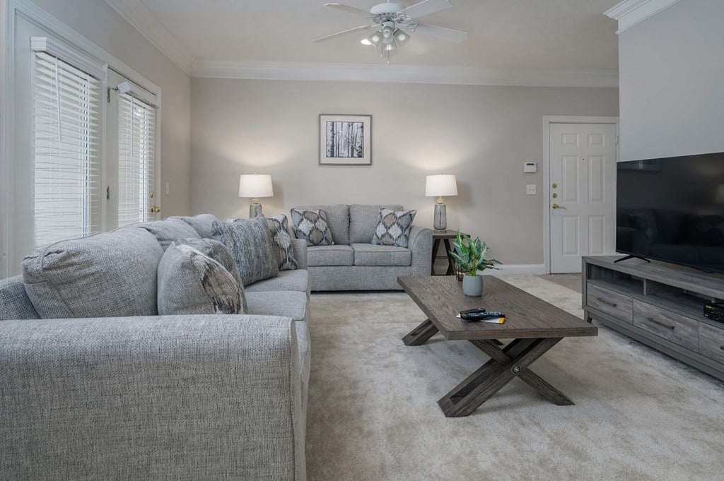 A living room with a grey couch, a wooden coffee table, and a flat screen TV.
