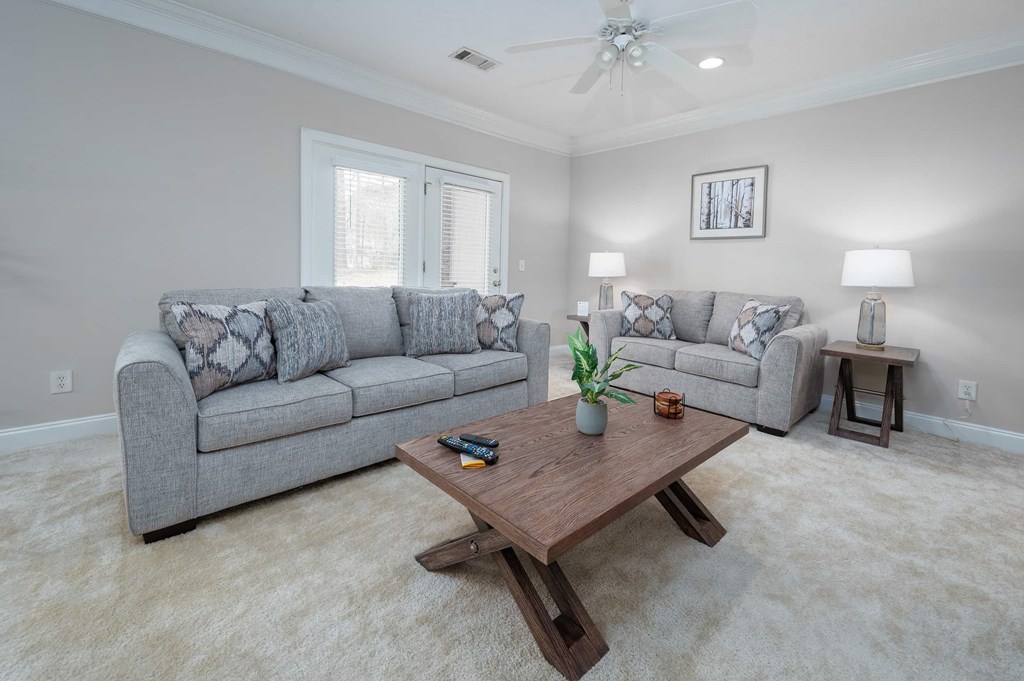 A living room with a grey couch, a wooden coffee table, and a ceiling fan.