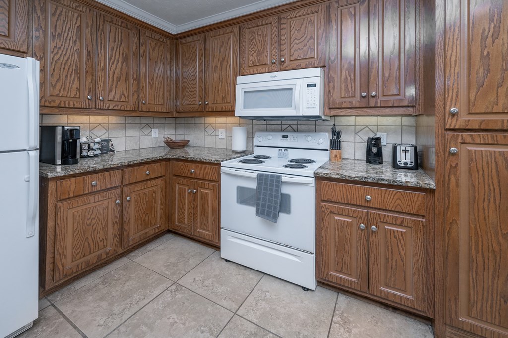 A kitchen with wooden cabinets and a white stove top oven.