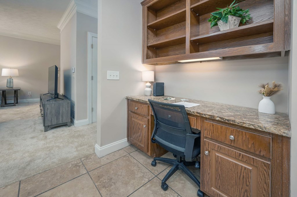 A black office chair is in front of a wooden desk with a speaker on it.