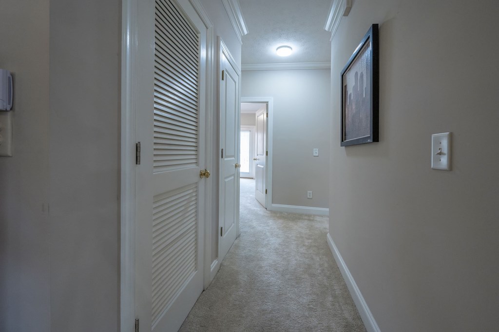 A hallway with a closed door on the left and a painting on the wall on the right.
