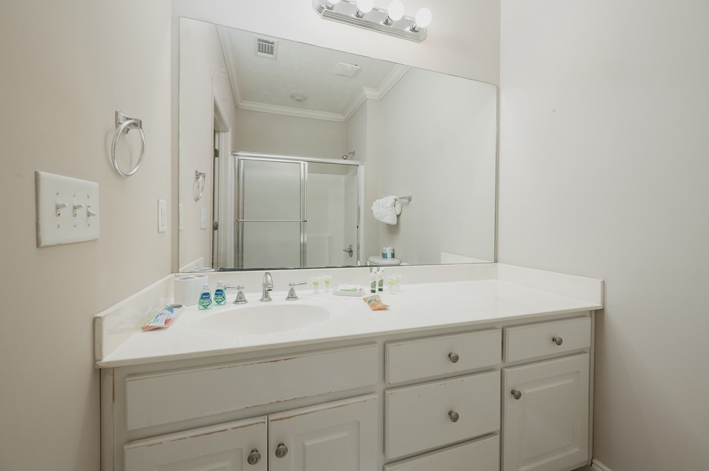 A white bathroom vanity with a mirror above it.