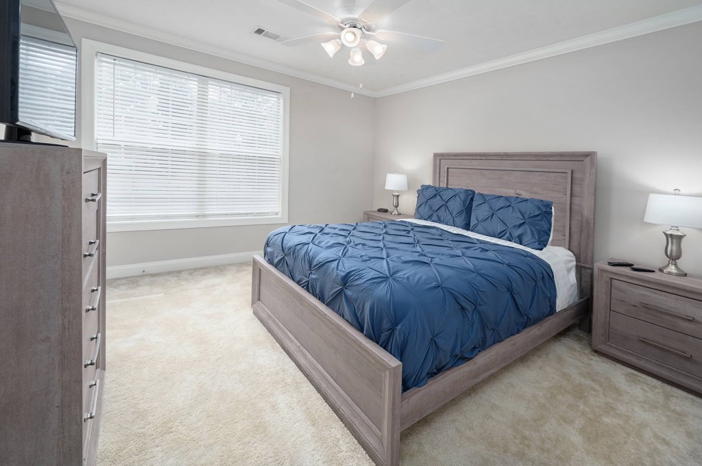 A bedroom with a large bed and a ceiling fan.