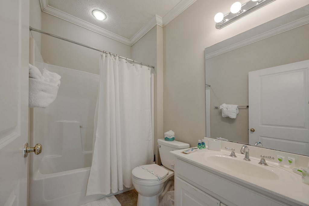 A white bathroom with a toilet, sink, and shower.