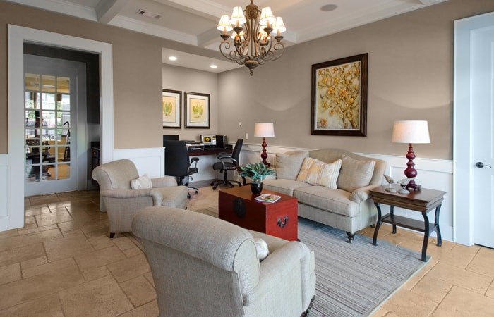 A living room with a grey sofa, a red side table, and a chandelier.