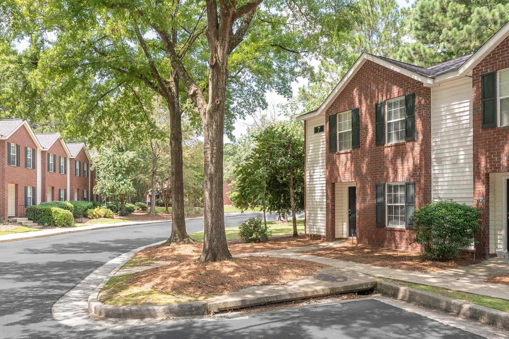A tree in front of a building with a red brick wall.
