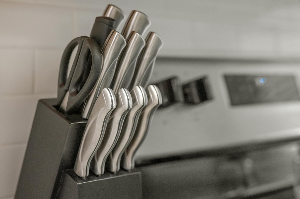 A set of knives is displayed on a block in a kitchen.