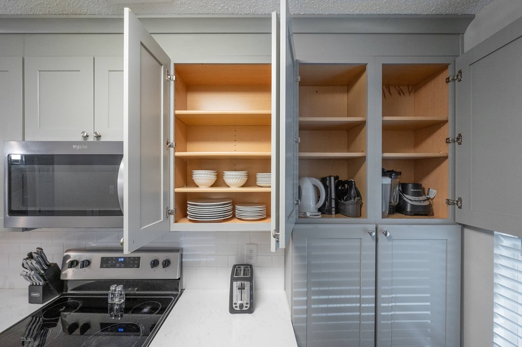 A modern kitchen with a stove, microwave, and open cabinets.