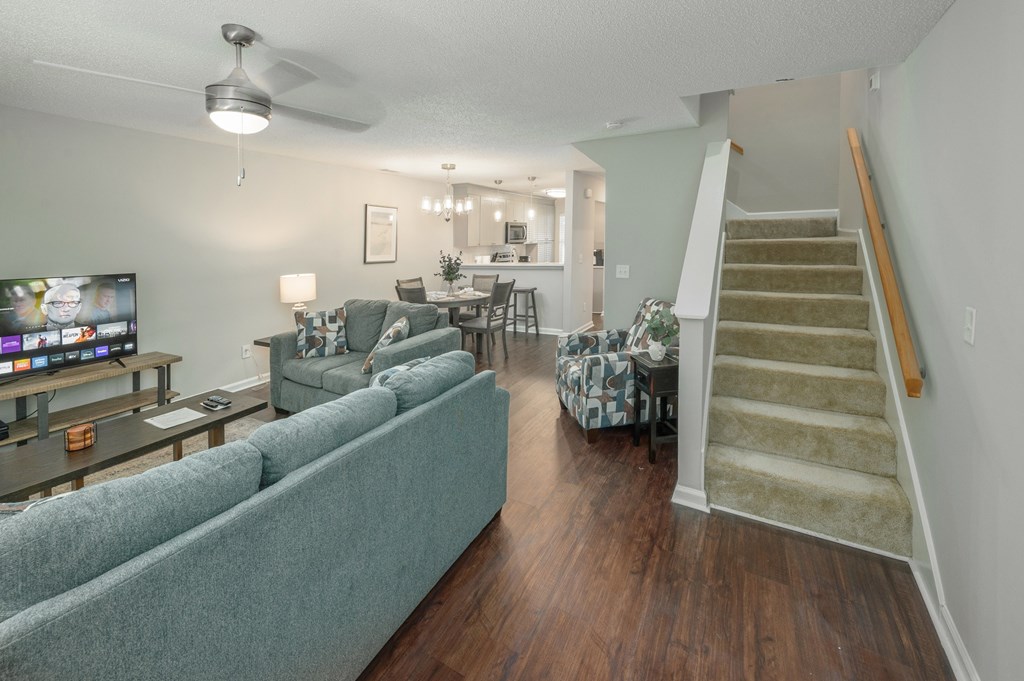 A living room with a couch, a television, and a staircase.