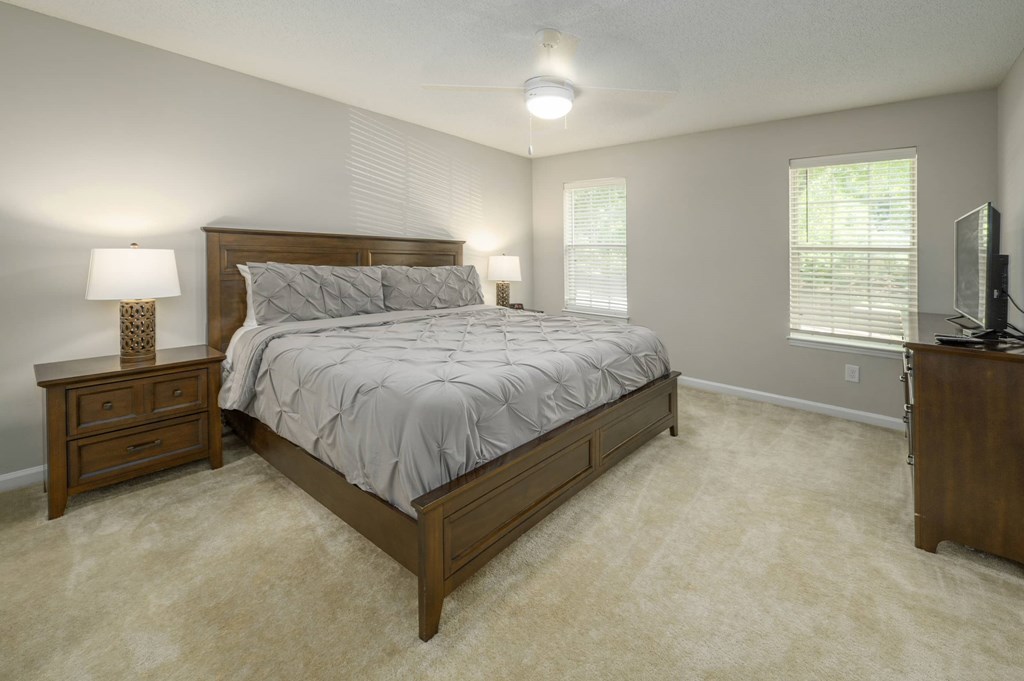A bedroom with a large bed, a nightstand, and a television.