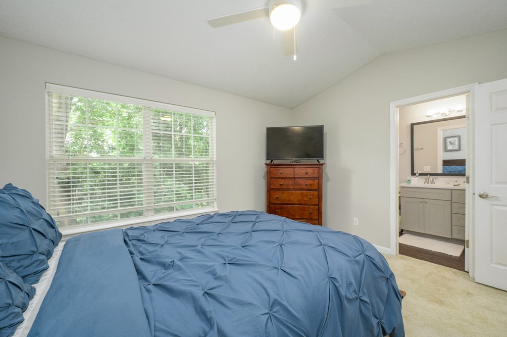 A bedroom with a bed, dresser, and television.